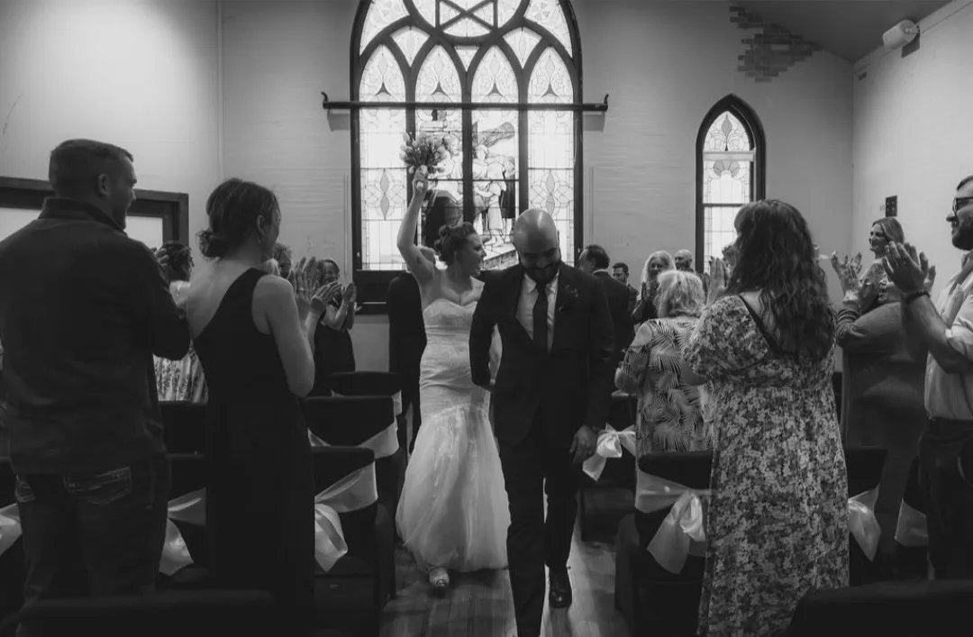 Newlyweds walk back down the aisle to applause beneath the stained glass